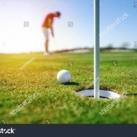 stock-photo-golfer-putting-golf-ball-on-the-green-golf-lens-flare-on-sun-set-evening-time-professional-golf-1722156607 