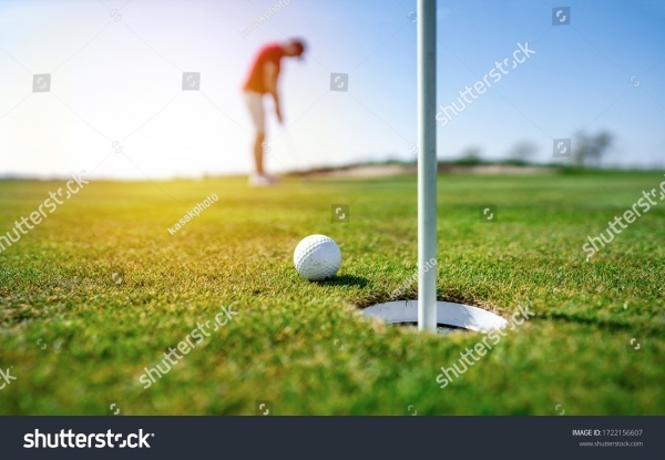 stock-photo-golfer-putting-golf-ball-on-the-green-golf-lens-flare-on-sun-set-evening-time-professional-golf-1722156607